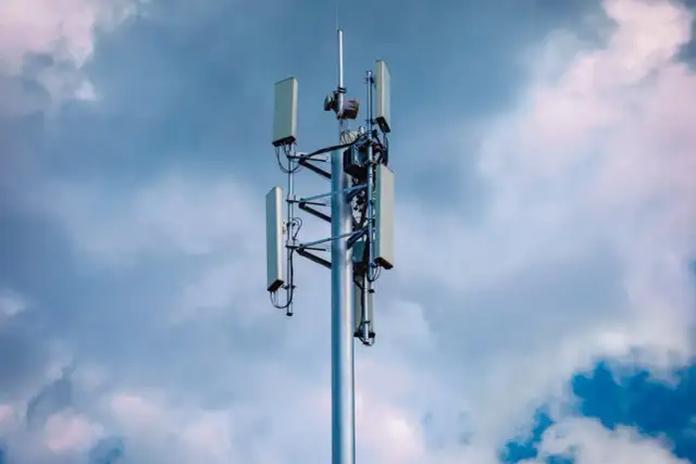 Wieża telekomunikacyjna z antenami, gotowa do obsługi sieci 5G, na tle burzowego nieba.