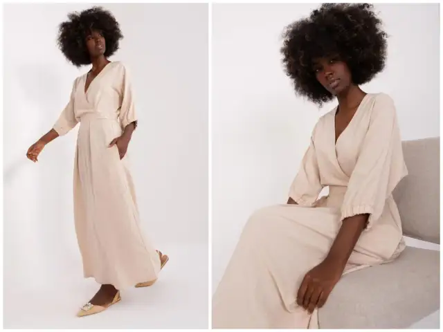 Kobieta w beżowej sukience empire, która podkreśla talię. Sukienka ma dekolt kopertowy i luźne rękawy.