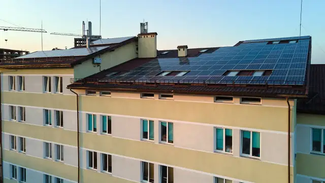 Budynek z panelami fotowoltaicznymi na dachu, wspierany przez Bank Gospodarstwa Krajowego.