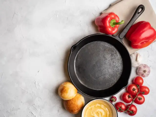 Żeliwna patelnia, papryki, pomidorki, czosnek i bułeczki. Zastanawiasz się, jakich patelni należy unikać? Ta wygląda na solidną.