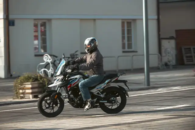 Mężczyzna w kasku jedzie na motocyklu Barton, który wygląda jak największy motocykl 125.