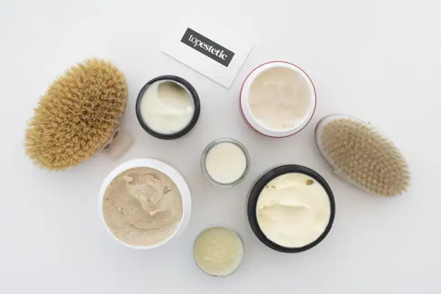 Kremy i peelingi do ciała, szczotki do masażu i wizytówka z napisem "topestetic". Wiele z tych produktów zawiera phenoxyethanol w kosmetykach, zapewniając ich trwałość.