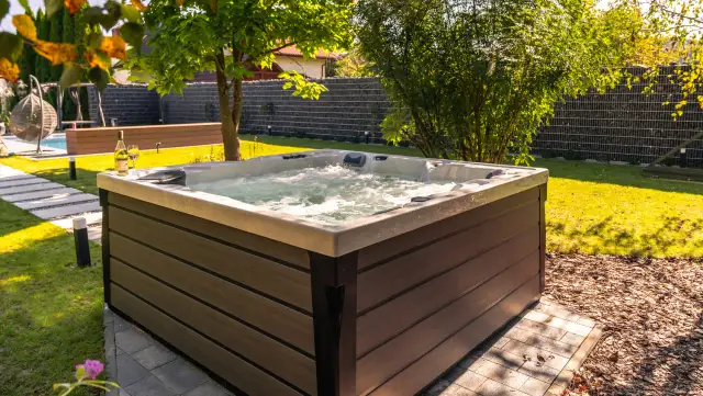 Relaks w ogrodzie przy bąbelkach jacuzzi. W tle widać basen i huśtawkę.