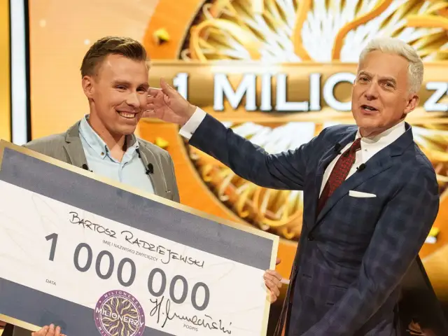 Bartosz Radziejewski, który wygrał milion w Milionerach, odbiera czek z nagrodą od Huberta Urbańskiego.