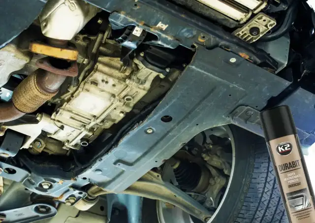 Konserwacja podwozia bez kanału: widok od spodu samochodu, skrzynia biegów, elementy zawieszenia i puszka preparatu do ochrony podwozia.