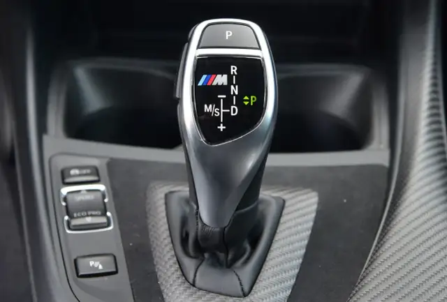 Bieg P, R, N, D, M/S na dźwigni skrzyni automatycznej BMW M. Oznaczenia biegów są czytelne.