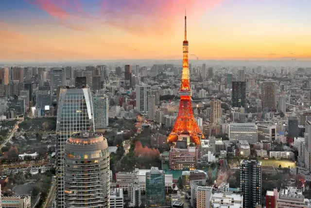 Widok na Tokio, jedno z 10 największych miast na świecie, z wieżą Tokyo Tower w pomarańczowych barwach o zachodzie słońca.