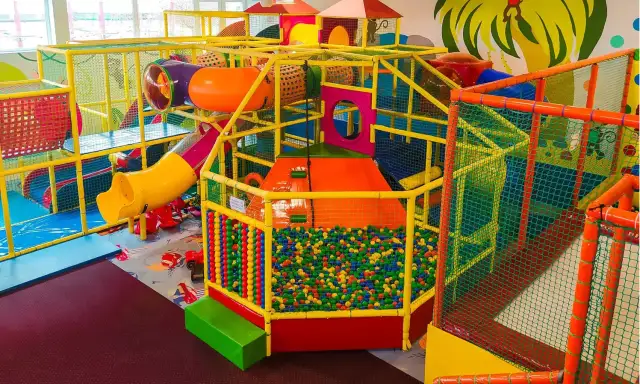 Kolorowy, wielopoziomowy plac zabaw z tunelami, zjeżdżalniami i basenem z kulkami.