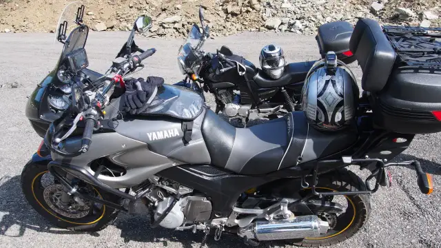 Dwa motocykle Yamaha zaparkowane na drodze szutrowej, jeden z kaskiem na siedzeniu.