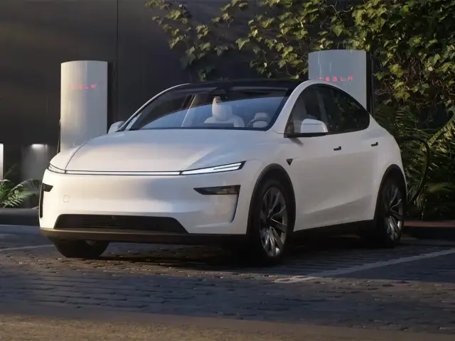 Biała Tesla zaparkowana przy ładowarce Supercharger.