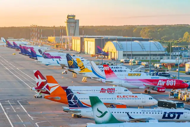 Samoloty pasażerskie zaparkowane na lotnisku o zachodzie słońca.