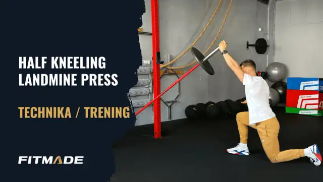 Mężczyzna w pozycji wykrocznej wykonuje ćwiczenie half kneeling landmine press.