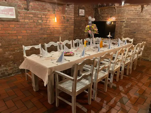 Ustawiony stół w restauracji z białymi obrusami, serwetkami, kwiatami i balonami.