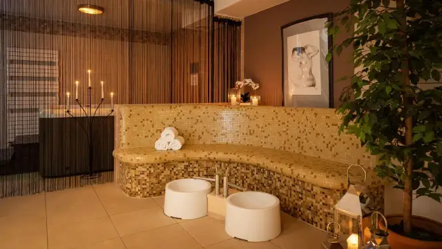 Relaks w spa: mozaikowa ławka, świece, wanna i rośliny tworzą atmosferę spokoju.