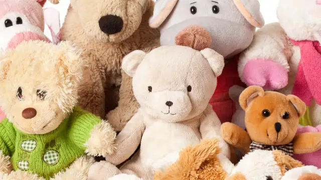 Grupa pluszowych misiów i innych zabawek na białym tle.