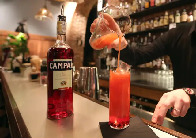 Barman nalewa drink z Campari do szklanki. Aperol kontra Campari - wybór należy do Ciebie!