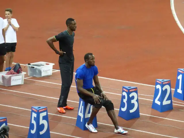 Usain Bolt, siedzący i stojący na bieżni, przypomina o jego rekordowej prędkości, która osiągnęła ponad 44 km/h.