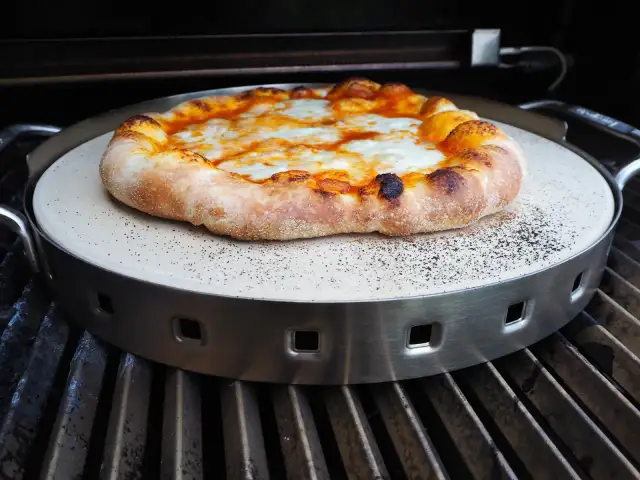 Pyszna pizza z grilla gazowego, z rumianym ciastem i ciągnącym się serem, pieczona na kamieniu.