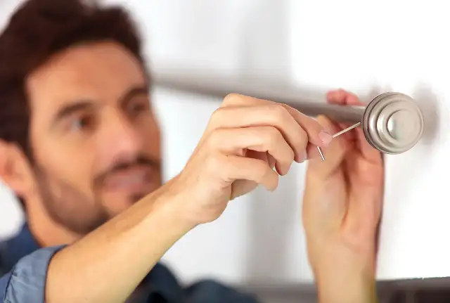 Mężczyzna montuje karnisz, używając małego klucza imbusowego.