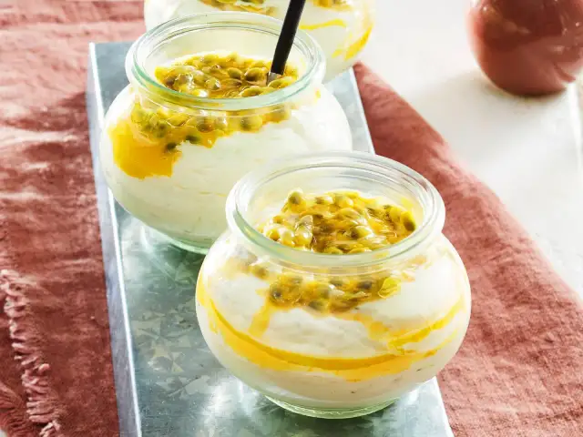 Zwei Gläser mit cremigem Dessert und Passionsfrucht-Topping.