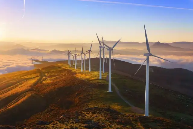 Wiatraki na wzgórzu o zachodzie słońca. Widać, jak działa turbina wiatrowa, łapiąc energię z wiatru.