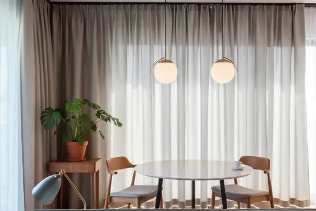 Nowoczesne rozwiązanie co zamiast karnisza w salonie: zasłony upięte na szynie sufitowej, tworzące miękkie fale.