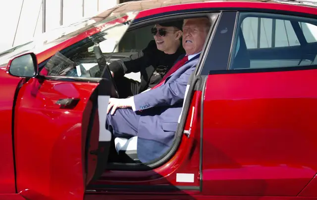 Elon Musk i Donald Trump siedzą w czerwonym samochodzie Tesla.