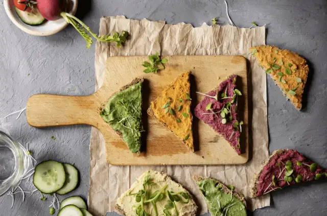 Kolorowe pasty na chlebie, zielona, pomarańczowa i fioletowa. Zastanawiasz się, jakie masło roślinne najzdrowsze? Te wyglądają apetycznie!