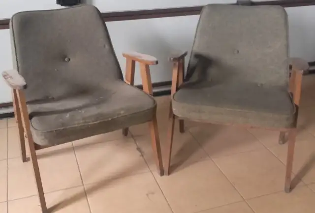 Dwa fotele w stylu Józefa Chierowskiego, z zieloną tapicerką i drewnianymi elementami, stoją na kafelkach.