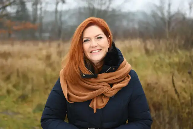 Uśmiechnięta Kasia w rudych włosach, otulona szalikiem, cieszy się listopadowym dniem.