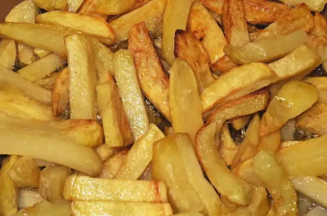 Złociste frytki smażące się na głębokim oleju, widok z góry.