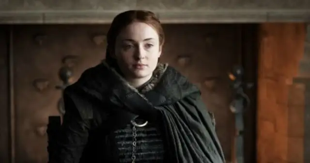 Sophie Turner w mrocznym stroju, przypominającym postać z Gry o Tron. Jej filmy, seriale i programy to fascynująca podróż przez różne światy.