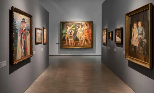 Wnętrze galerii sztuki z obrazami: portret mężczyzny, taniec postaci, portret dzieci.