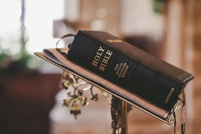 Czarna Biblia na złotym stojaku, z widocznym napisem "Holy Bible".