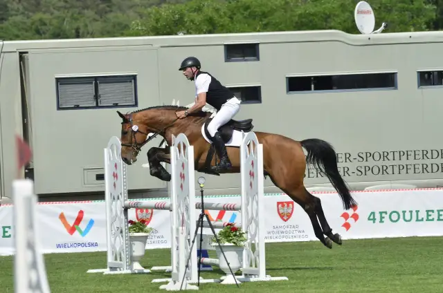 Jeździec na koniu pokonujący przeszkodę podczas zawodów jeździeckich.