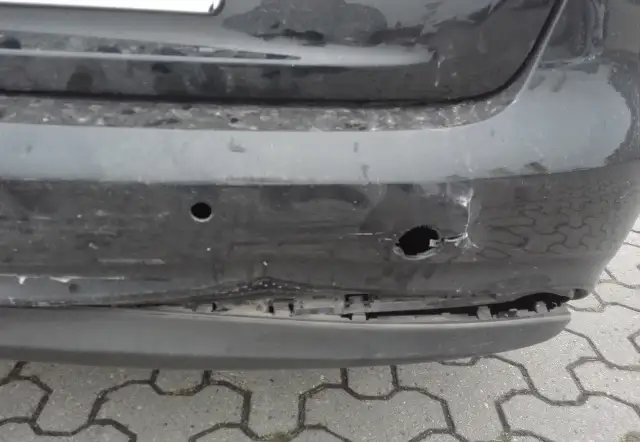 Uszkodzony zderzak po uderzeniu parkingowym: wgniecenia, pęknięcia i widoczne objawy uszkodzonych ślizgów zderzaka.