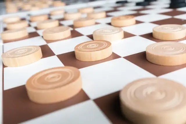 Drewniane pionki do gry w warcaby na planszy w kratkę.