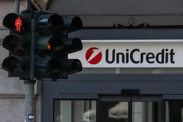 Czerwone światło dla pieszych i logo UniCredit. Czas na decyzję, kiedy wycofać się z funduszu inwestycyjnego.