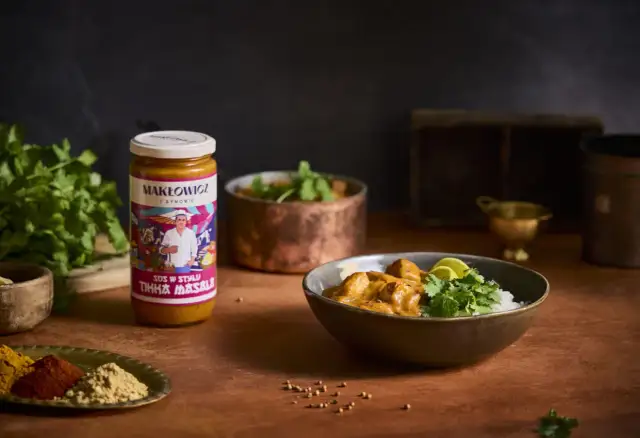 Słoik sosu Tikka Masala i miska z daniem z ryżem, kurczakiem i kolendrą.