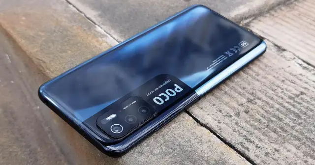 Czarny Xiaomi Poco M3 Pro z modułem aparatów 48MP AI VISION, leżący na kamiennym podłożu.