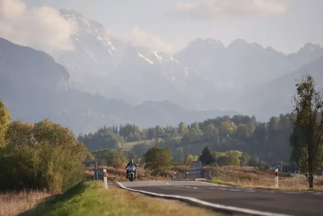Motocyklista na drodze w górach, jesienny krajobraz.