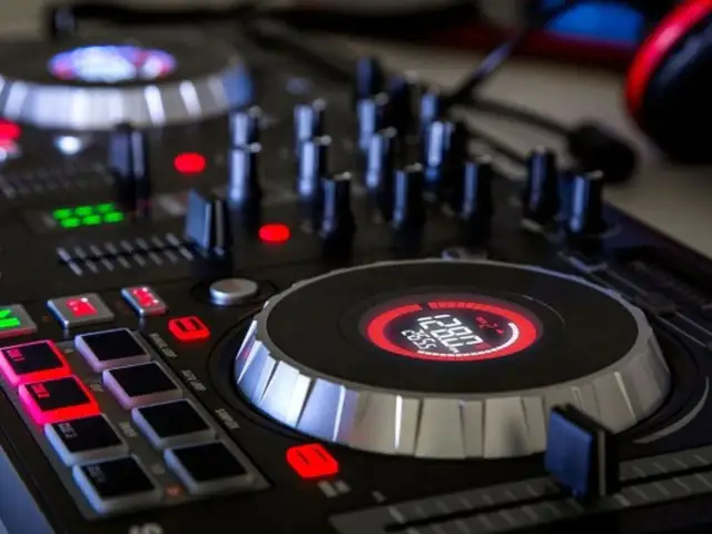 Zbliżenie na konsolę DJ-ską z podświetlanymi przyciskami i wyświetlaczem.