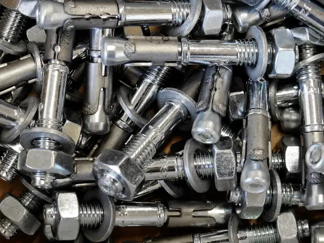Zbliżenie na metalowe kotwy chemiczne z nakrętkami i podkładkami.