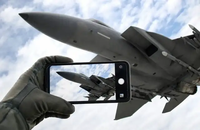 Ręka w rękawicy pilota trzyma smartfon, na którym widać myśliwiec. To jakby zapowiedź **Top Gun 3** – uchwycone w kadrze marzenie o przestworzach.