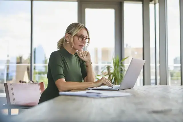 Kobieta w okularach pracuje na laptopie, szukając informacji, jak założyć konto w BIK.