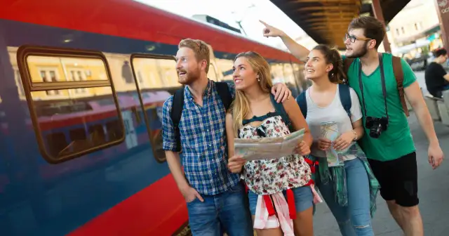 Grupa przyjaciół z mapą przy pociągu, zastanawia się, gdzie na majówkę pociągiem.
