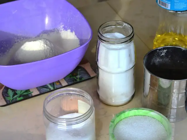 Filiżanki z mąką, cukrem i olejem na kuchennym blacie.