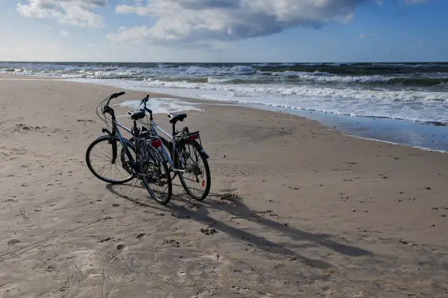 Dwa rowery na piaszczystej plaży nad Bałtykiem. Idealne, by jak zaplanować trasę rowerową wzdłuż polskiego wybrzeża etapami.