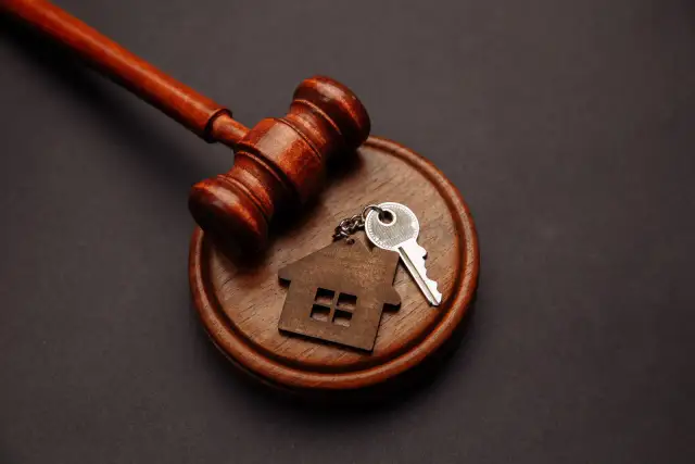 Młotek sędziowski, klucz i brelok w kształcie domu. Czy można wyrzucić z domu osobę zameldowaną na stałe? Prawo nieruchomości.