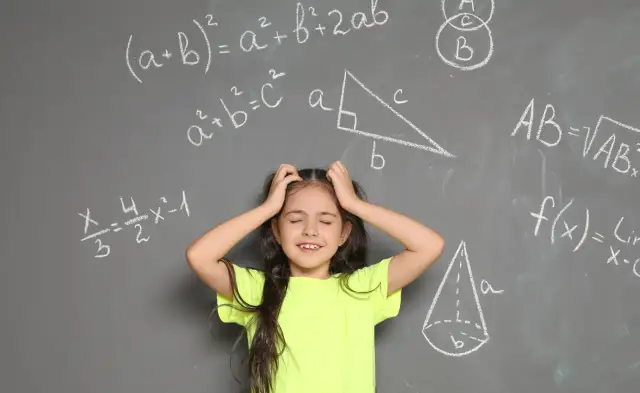 Dziewczynka z rękami wplątanymi we włosy, wyraźnie przeżywająca problemy z matematyką. Wokół niej wzory i figury geometryczne na tablicy.